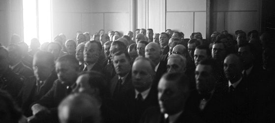 Mustavalkoinen valokuva, jossa kansanedustajat istuvat tiiviisti riveissä.