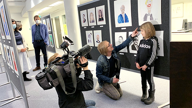 TV-haastattelussa pieni tyttö, joka on maalannut kansanedustajan muotokuvan.