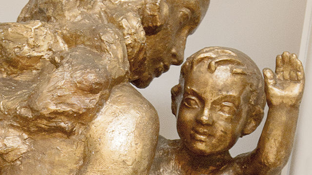 A gilded statue of a child waving their hand